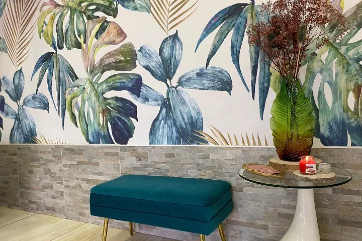 L'angolo d'attesa: panca in velluto verde petrolio, vaso di vetro verde e carta da parati con foglie tropicali blu e oro